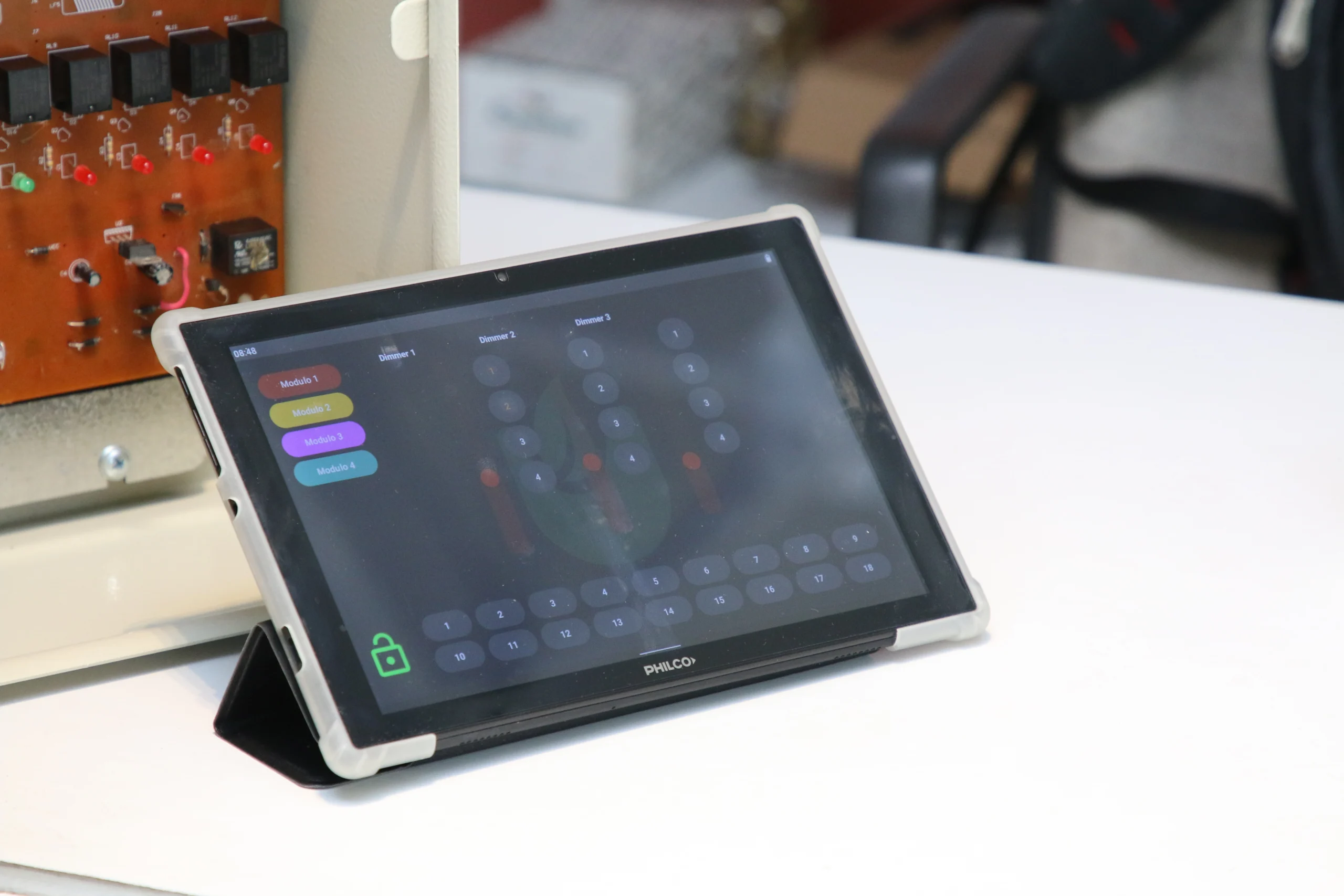 Tablet con interfaz de software SmartGlow controlando módulos de hardware para eficiencia energética y gestión de iluminación industrial.